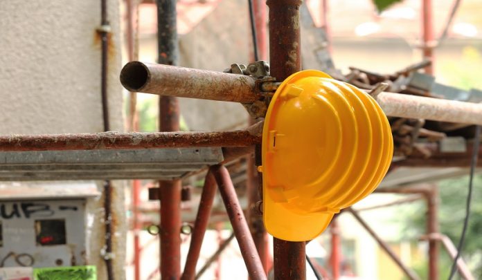 Yellow,Helmet,On,Tubular,Scaffolding,,Shallow,Dof Trauma da schiacciamento e decesso del lavoratore