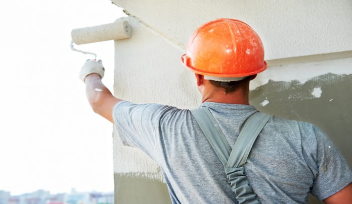 Young,Painting,Facade,Builder,Worker,With,Roller,At,Thermal,Insulation Infortunio dell'operaio durante i lavori di pittura dell'edificio