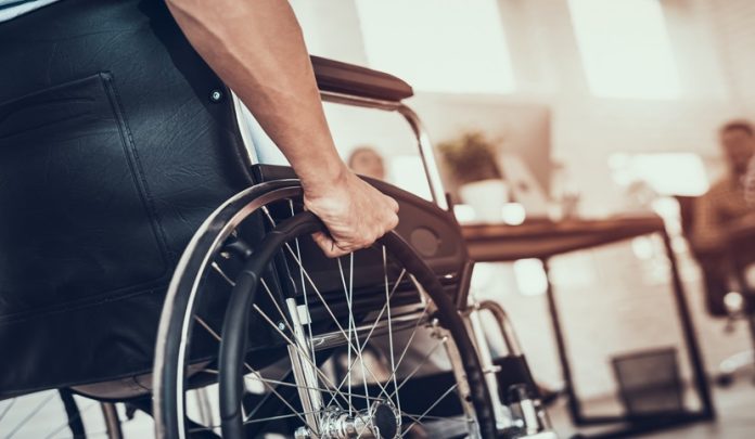 Close,Up.,Disabled,Man,On,Wheelchair,In,Office.,Disabled,Young Indennità di accompagnamento e requisiti per l'ottenimento