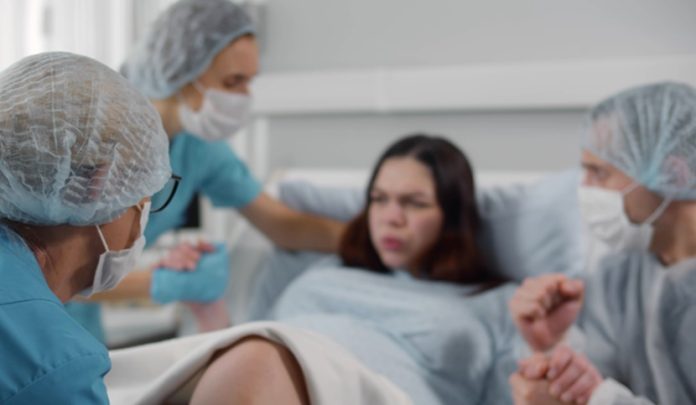 Pregnant,Woman,In,Hospital,Giving,Birth,With,Husband,In,Mask Eclampsia al momento del parto e gravissime lesioni permanenti